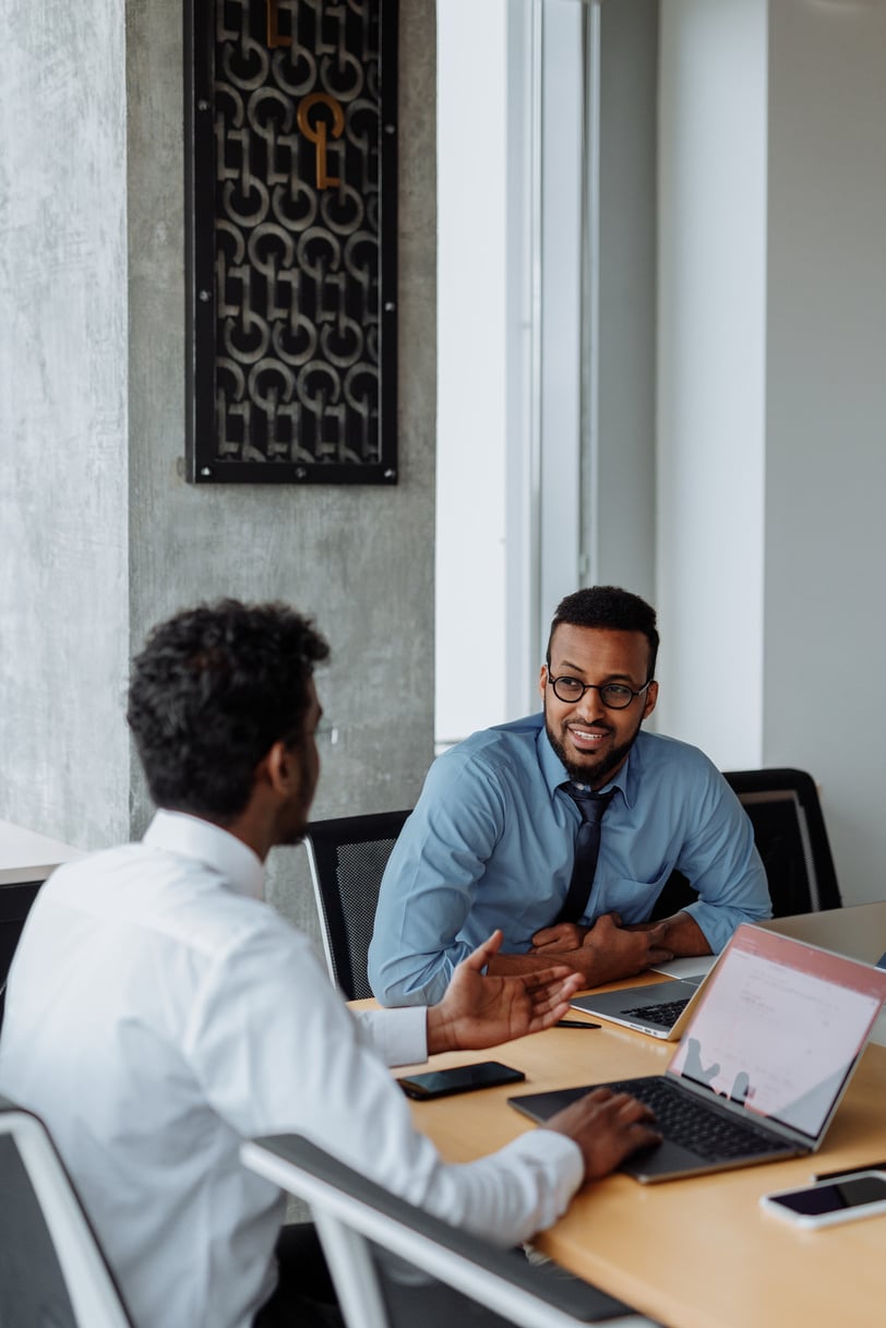 Two Men Sitting at Table and Talking in the Office